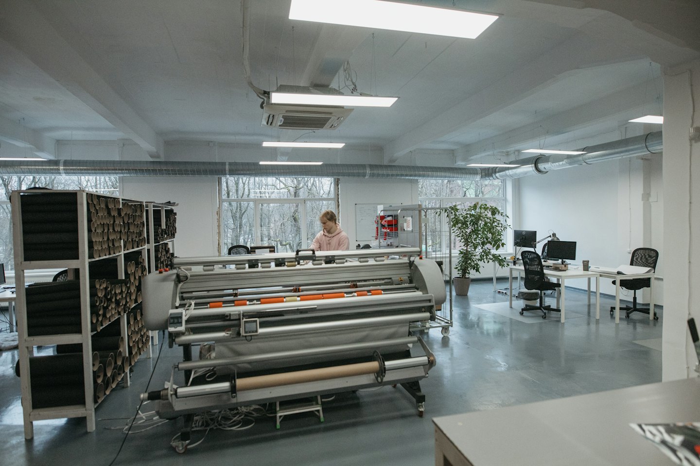 Person operating a large format industrial printer in a workshop.