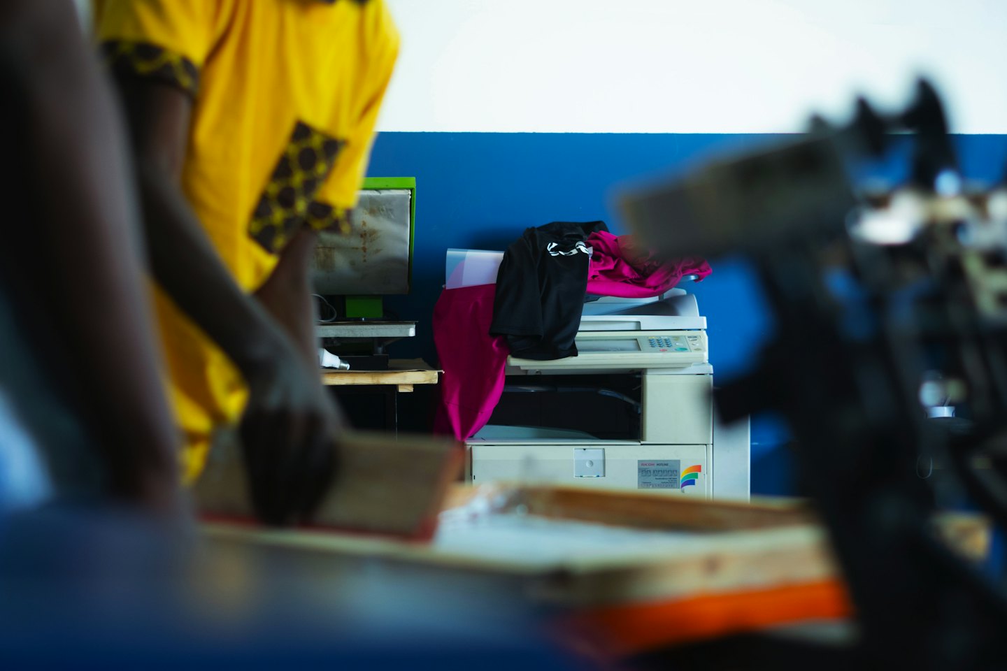 Person screen printing a t-shirt with a squeegee.